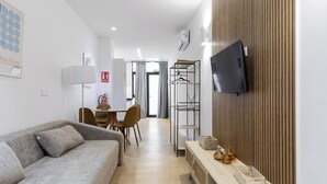 En moderne stue med en grå sofa, et træskab og et fjernsyn monteret på væggen.