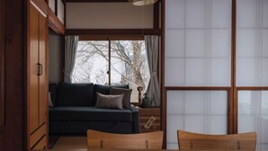 A traditional Japanese room with tatami flooring, a dark blue sofa, a wooden table, and a sliding shoji screen.