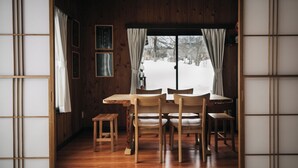 A traditional Japanese room with tatami flooring, a low wooden table, and a view of a snowy landscape through a sliding door.