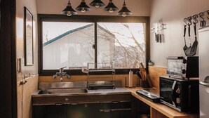 A compact kitchen with a wooden countertop, a sink, a microwave, and hanging utensils.
