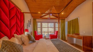 A bedroom with a large bed, red upholstered headboard, wooden ceiling, and a view of the outdoors through a window. - Hyacinth Hotel (Manali)