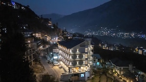 A multi-story hotel with a central courtyard, surrounded by a mountainous landscape. - Hyacinth Hotel (Manali)