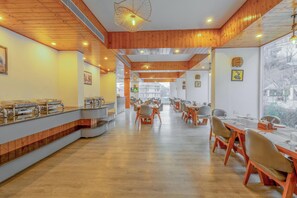 A spacious dining area with wooden paneling, long tables, and chairs. - Hyacinth Hotel (Manali)