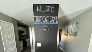 A hallway with a black door labeled "WELCOME TO FIRST COAST ESCAPE" and a small sign with colorful letters.