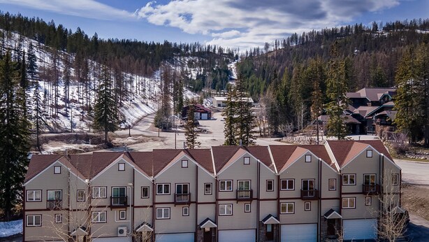 A multi-story residential building with a symmetrical facade, multiple balconies, and a garage entrance. - Ski in/walk out, Jetted tub, close to Whitefish Lake (Whitefish)