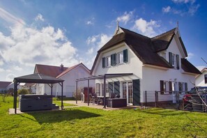 Une maison à deux étages avec un patio couvert et une cour clôturée.