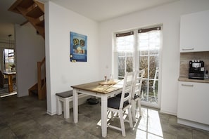 A kitchen with a dining table, chairs, a coffee machine, and a window with frosted glass.