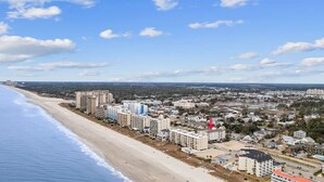 Un paysage urbain côtier avec une zone hôtelière en bord de mer, comprenant des immeubles de grande hauteur et une plage.