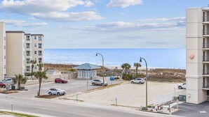 Une vue sur la plage, avec un parking, un petit bâtiment et la plage en arrière-plan.