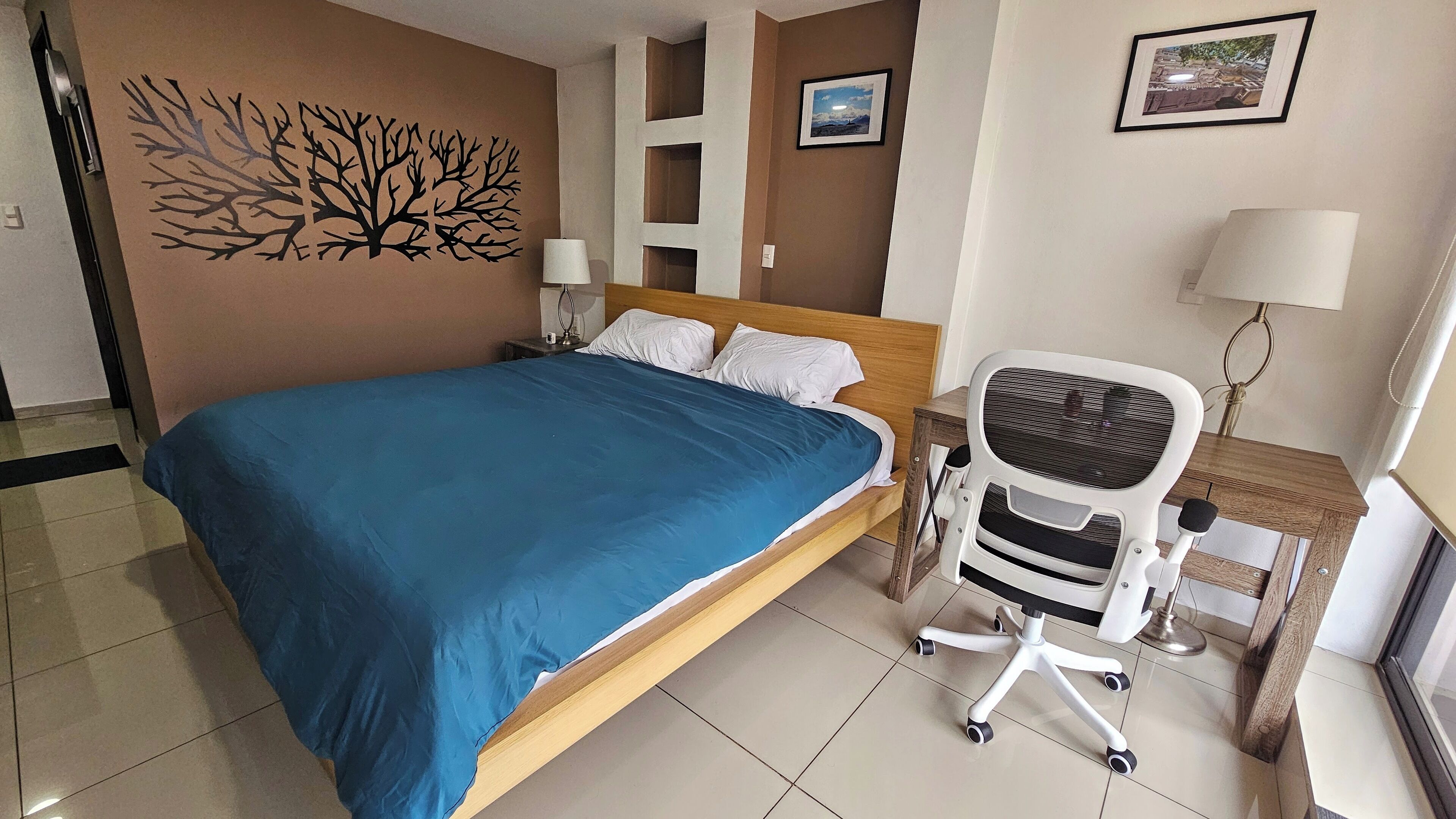 A hotel room with a bed, a desk, and a chair.