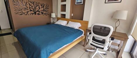 A hotel room with a bed, a desk, and a chair.