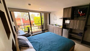 Un dormitorio con una cama grande, una kitchenette pequeña y vistas al exterior.