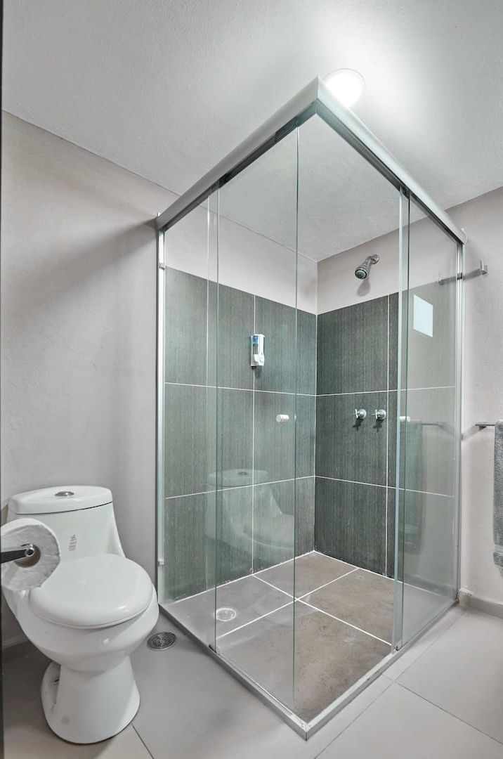 A modern bathroom with a glass-enclosed shower, a toilet, and a tiled floor.