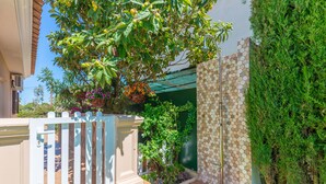 A well-maintained garden with a white picket fence, a tiled patio, and a variety of plants and flowers.