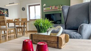 A cozy living room with a wooden coffee table, two red candles, a potted plant, and a grey sofa. - Auszeit by Interhome (Oy-Mittelberg)