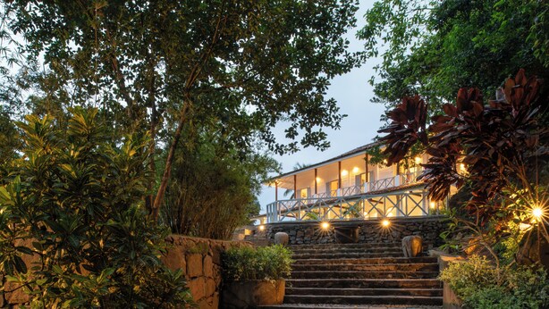 A stone staircase leading to a building with a balcony, surrounded by lush greenery and stone walls. - Villa Poojakanda (Koggala)