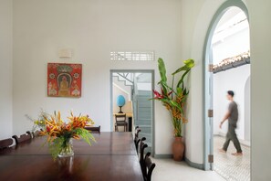A dining area with a wooden table, chairs, a vase of flowers, a globe, and a staircase leading to another room. - Villa Poojakanda (Koggala)