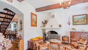 Un salon rustique, avec des meubles en bois, une cheminée et un escalier menant à un autre niveau.