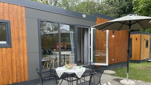 A modern outdoor dining area with a table and chairs, a wooden deck, and a dog.