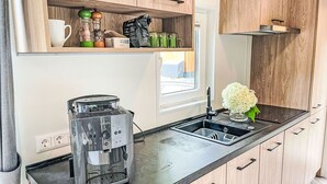 A modern kitchen with wooden cabinets, a black countertop, a coffee maker, and a window with a view.