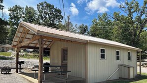 A small, single-story building with a covered porch and a picnic table. - Norfork Lake - Quaint 2 bedroom, no stairs. By the pool -camp store - pavilion. (Elizabeth)