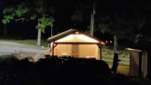 A small, single-story building with a sloped roof, illuminated by warm interior lighting. - Norfork Lake - Quaint 2 bedroom, no stairs. By the pool -camp store - pavilion. (Elizabeth)