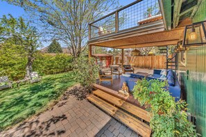 A modern house with a glass conservatory, outdoor seating area, and a wooden deck.