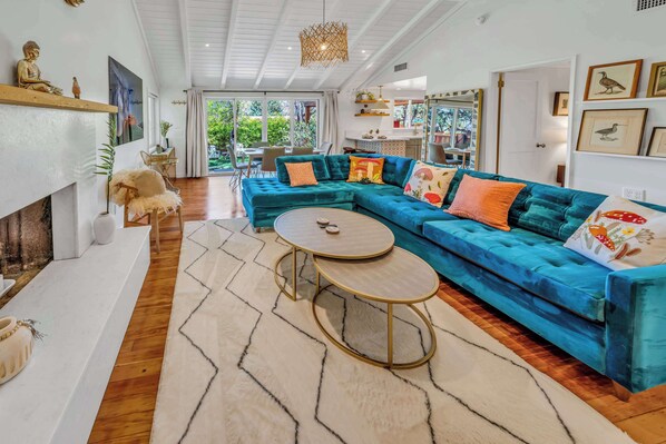 A modern living room with a teal sectional sofa, a round coffee table, and a fireplace.