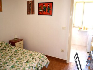A bedroom with a bed, a nightstand, a chair, and a window. - Kitai Air-conditioned Studio Holiday Home in San Foca (Melendugno)