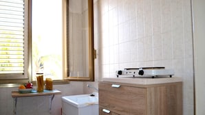 A small kitchen with a window, a sink, a stove, and a cabinet. - Kitai Air-conditioned Studio Holiday Home in San Foca (Melendugno)