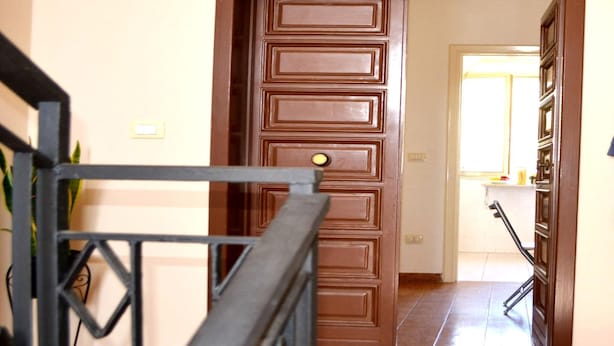 A hallway with a wooden door, a metal railing, and a tiled floor. - Kitai Air-conditioned Studio Holiday Home in San Foca (Melendugno)