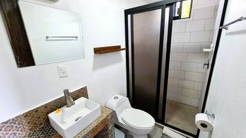 A bathroom with a white sink, toilet, and shower.