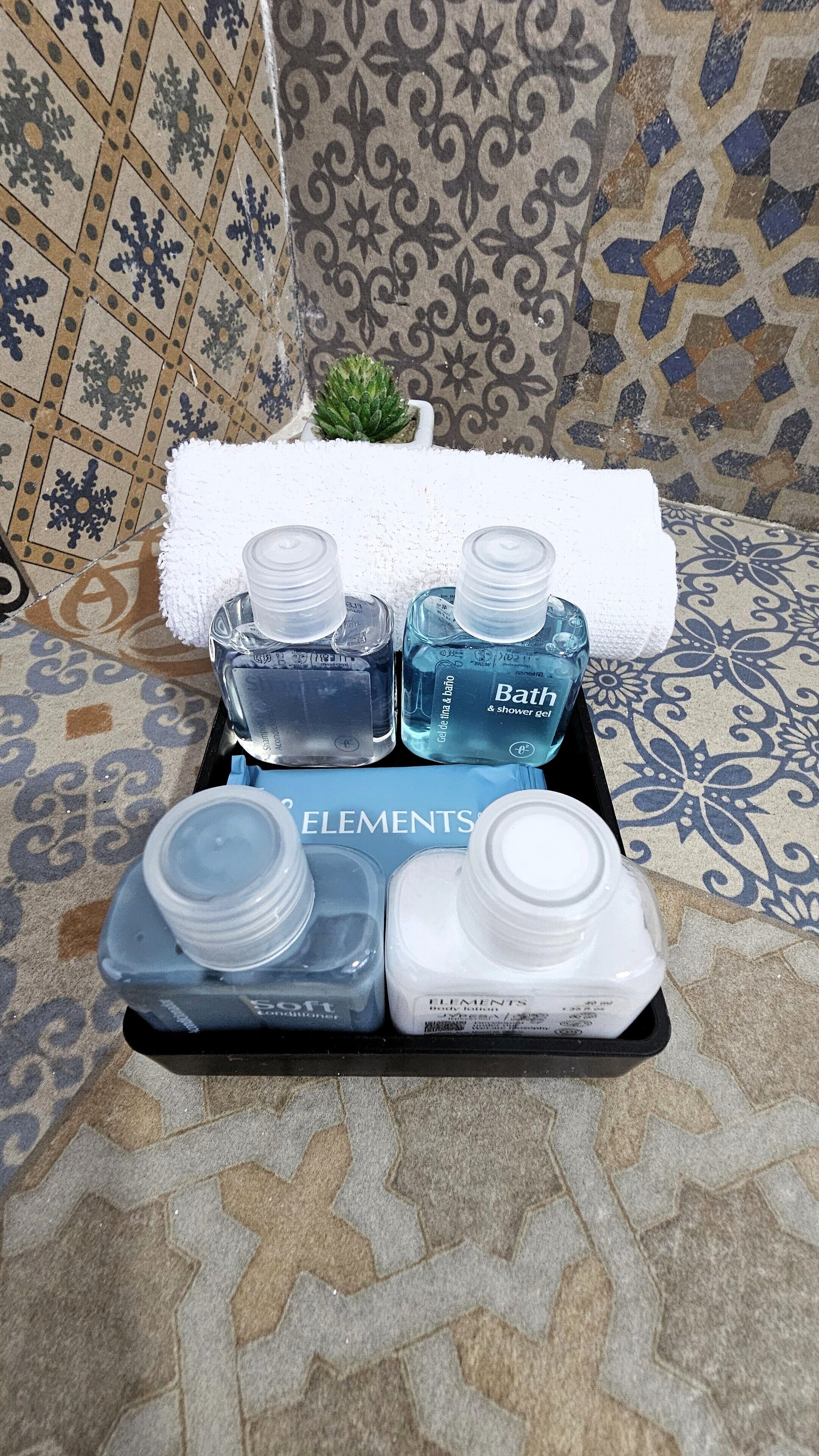 A tray with toiletries including a bottle of bath and shower gel, a bottle of body lotion, and a container of cotton swabs.