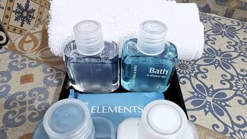 A tray with toiletries including a bottle of bath and shower gel, a bottle of body lotion, and a container of cotton swabs.