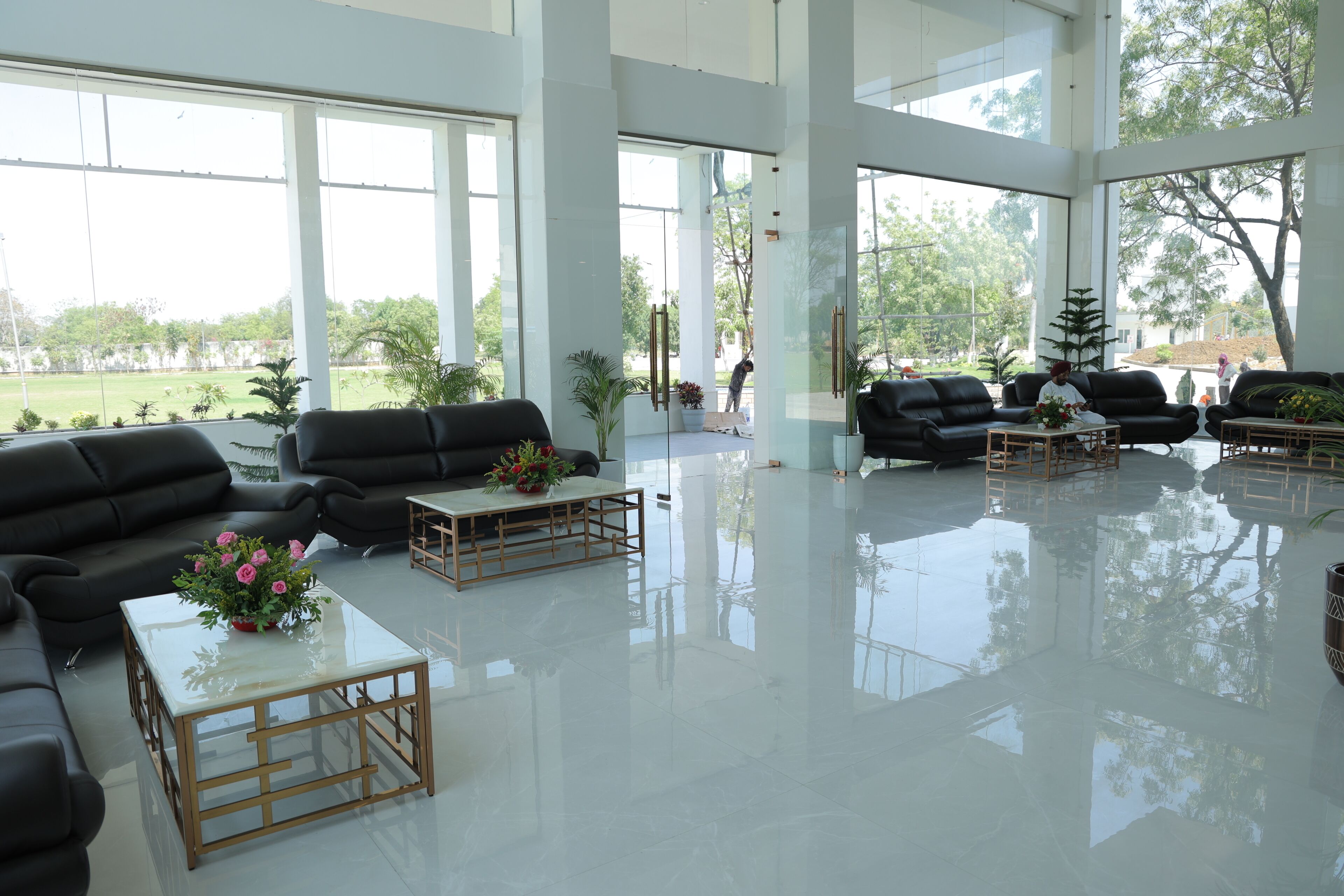 A spacious lobby with large windows, black leather sofas, and a polished floor.