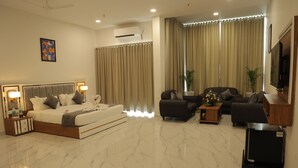 A modern hotel room with a large bed, a sofa, a TV, and a small table. - Hotel The City Crown-Bilaspur (Bilaspur)