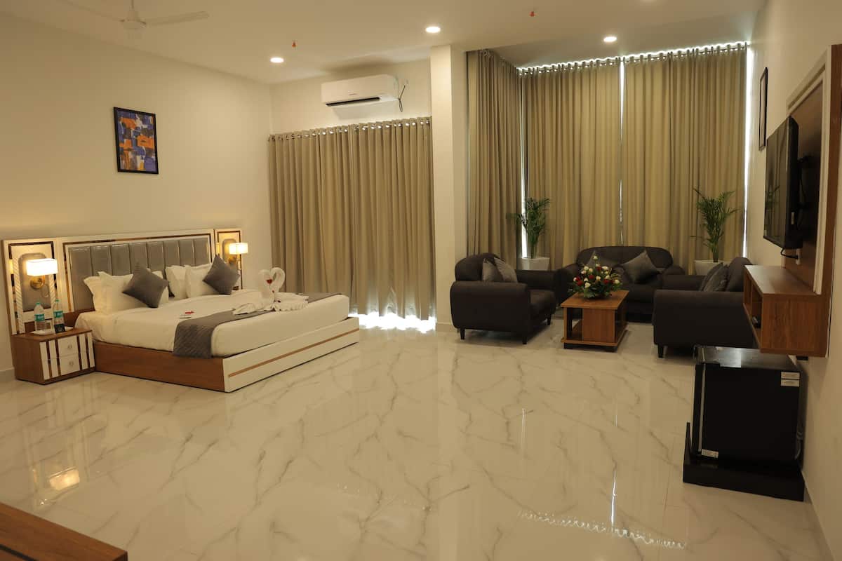 Une chambre d’hôtel moderne avec un grand lit, un canapé, une télévision et une petite table.