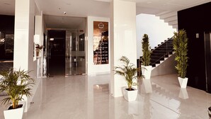 A modern lobby with a glass entrance, a staircase, and potted plants. - Hotel The City Crown-Bilaspur (Bilaspur)