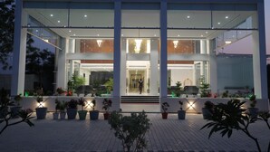 A modern building with a glass facade, a central entrance, and potted plants around the entrance area. - Hotel The City Crown-Bilaspur (Bilaspur)