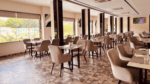 A spacious restaurant with high ceilings, modern lighting, and large windows offering views of the outdoors. - Hotel The City Crown-Bilaspur (Bilaspur)