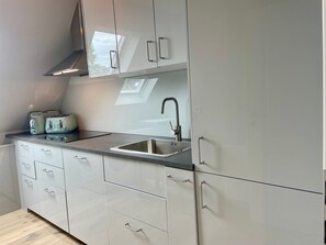Eine moderne Küche mit Spüle aus Edelstahl, einem Fenster über der Arbeitsplatte und einem eingebauten Backofen.