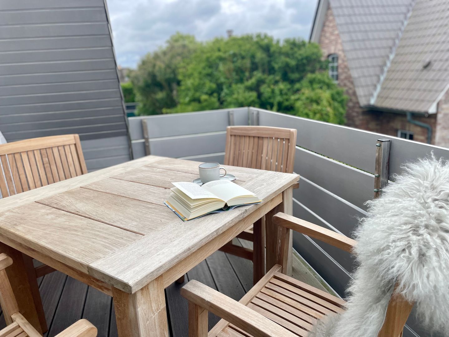 A wooden deck with a table and chairs, a book, and a cup.