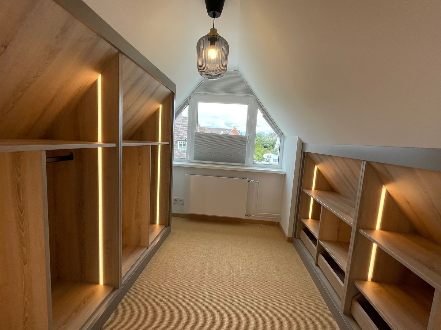 A narrow, wooden-paneled hallway with built-in shelving and a sloped ceiling.