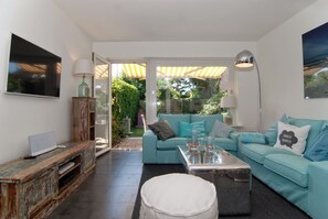 A modern living room with a teal sofa, a coffee table, a TV, and a wooden cabinet.