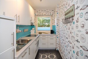 A compact kitchen with white cabinets, a sink, and a window with a view of greenery outside.