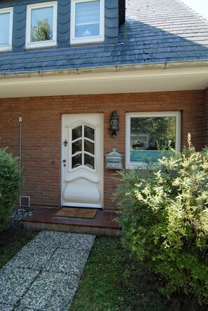 A house with a brick facade, a white front door, and a small window. - Ferienhaus Westhüs - Modernes, Renoviertes Reihenendhaus in Tinnum mit 95qm für bis zu 6 Personen! (Sylt)