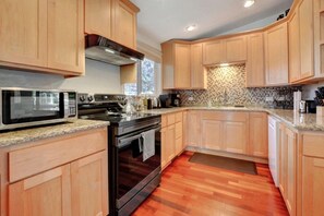 Une cuisine moderne avec des meubles en bois, un four à micro-ondes en acier inoxydable, une cuisinière à gaz et un plan de travail en granit.