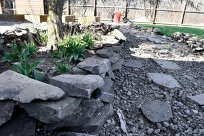 A garden with a rock border, plants, and a wooden fence in the background. - Spacious Family Home w/Hot Tub! Medford, OR (Medford)