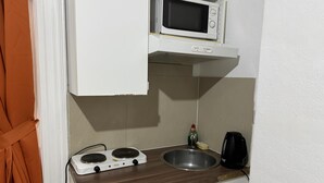 A compact kitchenette with a microwave, stove, sink, and a small bottle of dish soap. - Studio Apartment Sleeps 2 with Ensuite (London)