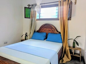 Un lit avec une tête de lit en bois, deux oreillers bleus et un couvre-lit blanc.